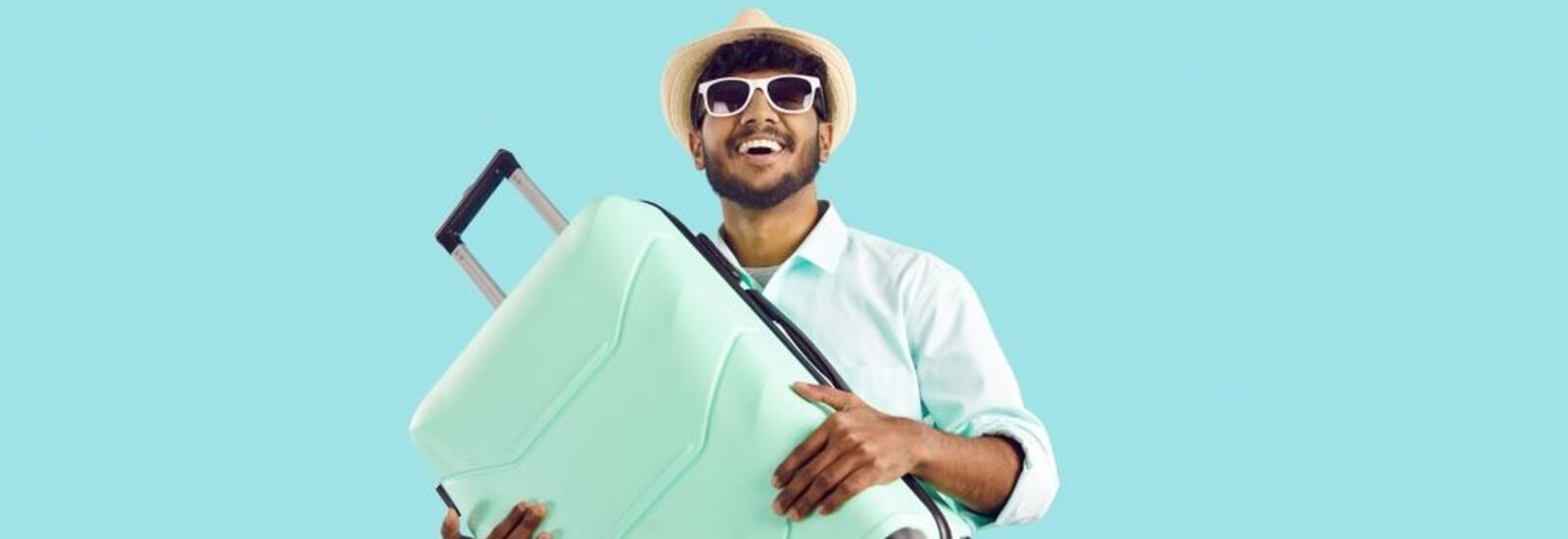 Man smiling holding light blue luggage